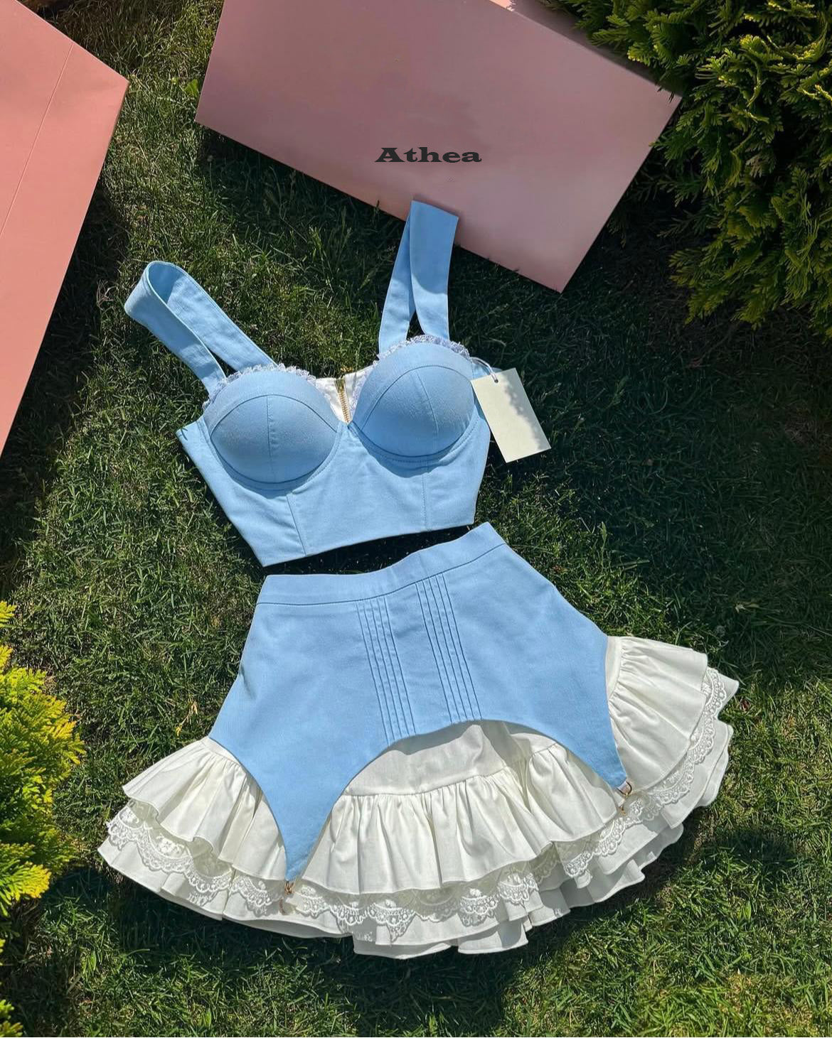Compleu damă elegant roz Norina by Athea, format din corset sexy cu dantelă albă și fustă mini cu volane, ideal pentru ocazii speciale, evenimente, petreceri sau ședințe foto. Ținută feminină de vară, outfit trendy 2025, haine elegante pentru femei moderne.